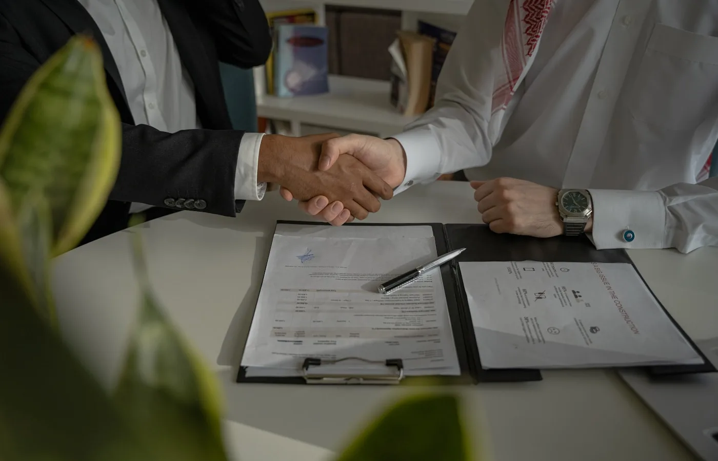 Two people shaking hands over a signed document